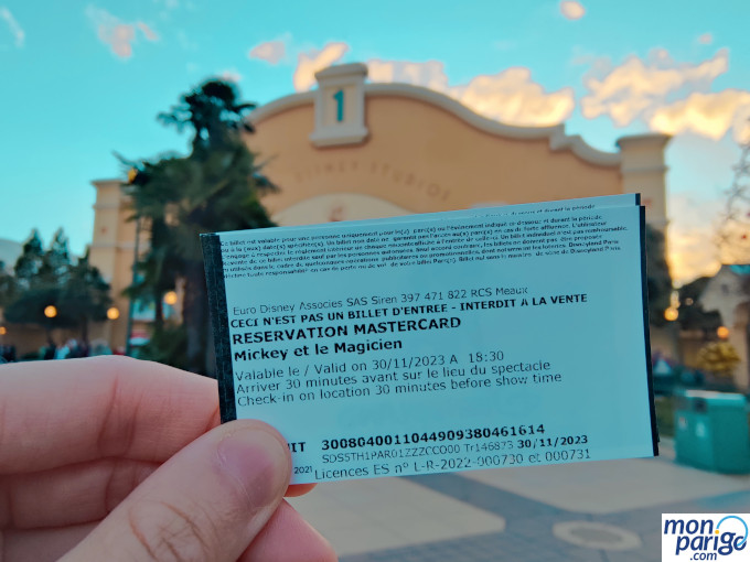 Mano sujetando una entrada con asiento preferente a un espectáculo de Disneyland Paris con Mastercard