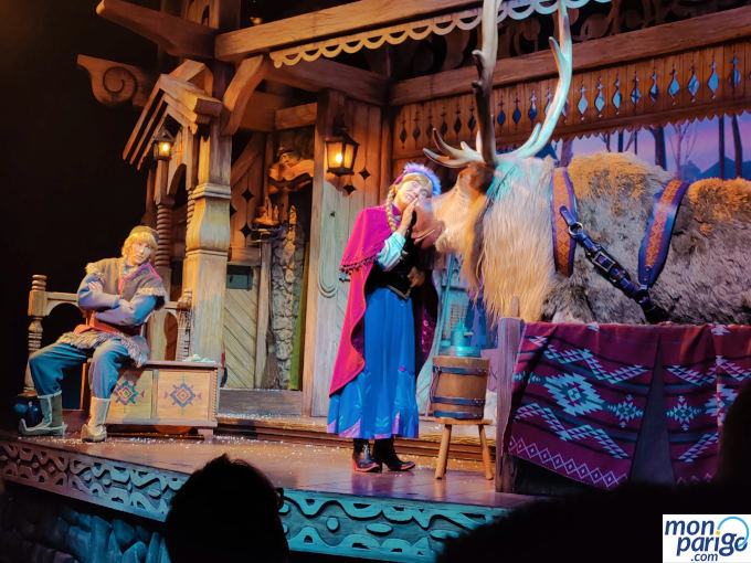 Anna acariciando a Sven junto a Kristoff en el granero del musical de Frozen en Disneyland Paris